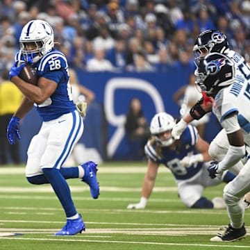 Oct 26, 2025; Indianapolis, Indiana, USA; Indianapolis Colts running back Jonathan Taylor (28) rushes as Tennessee Titans cornerback Jalyn Armour-Davis (18) defends during the first quarter at Lucas Oil Stadium. Mandatory Credit: Robert Goddin-Imagn Images