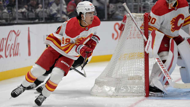 Hockey player in white uniform skates with the puc