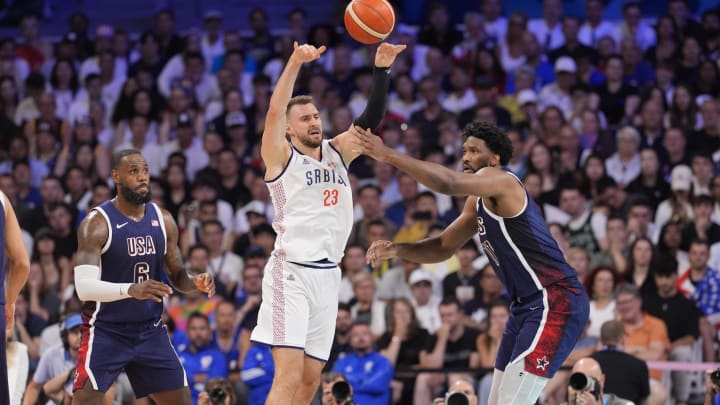 Jul 28, 2024; Villeneuve-d'Ascq, France; Serbia shooting guard Marko Guduric (23) passes against United States guard Lebron James (6) and center Joel Embiid (11) in the second quarter against Serbia during the Paris 2024 Olympic Summer Games at Stade Pierre-Mauroy. Mandatory Credit: John David Mercer-USA TODAY Sports