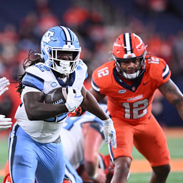Oct 31, 2025; Syracuse, New York, USA; North Carolina Tar Heels running back Demon June (12) runs between Syracuse Orange linebacker David Reese (left) and linebacker Anwar Sparrow (12) in the third quarter at the JMA Wireless Dome. Mandatory Credit: Mark Konezny-Imagn Images