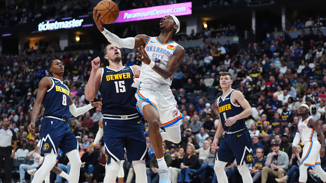 Nov 6, 2024; Denver, Colorado, USA; Oklahoma City Thunder guard Shai Gilgeous-Alexander (2) shoots the ball past Denver Nuggets center Nikola Jokic (15) in the second quarter at Ball Arena. Mandatory Credit: Ron Chenoy-Imagn Images