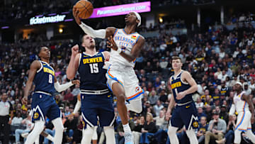 Nov 6, 2024; Denver, Colorado, USA; Oklahoma City Thunder guard Shai Gilgeous-Alexander (2) shoots the ball past Denver Nuggets center Nikola Jokic (15) in the second quarter at Ball Arena. Mandatory Credit: Ron Chenoy-Imagn Images