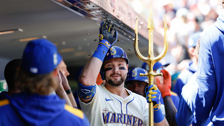 Cal Raleigh is celebrating a homerun by hoisting the Seattle Mariners' trident against the Tampa Bay Rays.