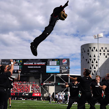 Oct 21, 2023; Cincinnati, Ohio, USA; The Cincinnati Bearcats mascot is thrown between cheerleaders in the first quarter at Nippert Stadium. Mandatory Credit: Kareem Elgazzar-Imagn Images