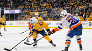 Apr 8, 2025; Nashville, Tennessee, USA;  Nashville Predators left wing Michael Bunting (58) blocks the pass of New York Islanders defenseman Alexander Romanov (28) during the third period at Bridgestone Arena. Mandatory Credit: Steve Roberts-Imagn Images