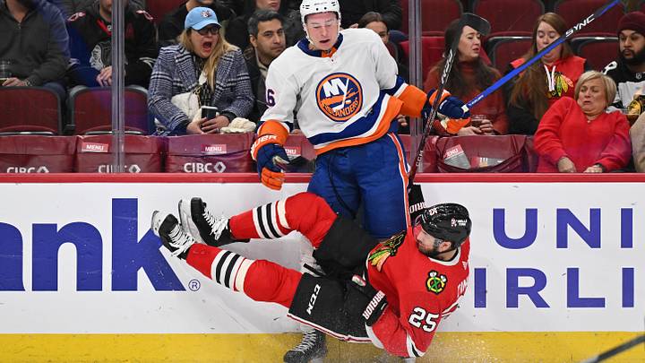 Jan 19, 2024; Chicago, Illinois, USA; Chicago Blackhawks defensman Jarred Tinordi (25) falls to the ice after checking New York Islanders forward Julien Gauthier (16) in the second period at United Center. Mandatory Credit: Jamie Sabau-Imagn Images
