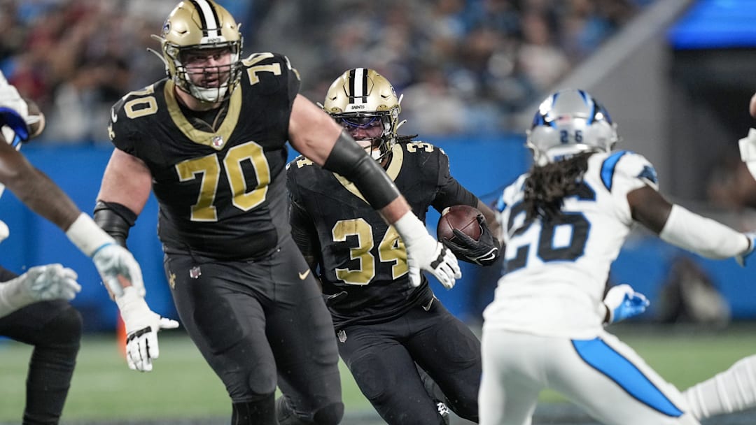 Sep 18, 2023; Charlotte, North Carolina, USA; New Orleans Saints running back Tony Jones Jr. (34) follows a block by offensive tackle Trevor Penning (70) against the Carolina Panthers during the second half at Bank of America Stadium. Mandatory Credit: Jim Dedmon-Imagn Images