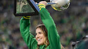 Oregon alum and New York Liberty player Sabrina Ionescu hoists the WNBA Finals trophy as the Oregon Ducks host the Maryland Terrapins at Autzen Stadium Saturday, Nov. 9, 2024 in Eugene, Ore.