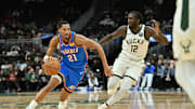 Oct 14, 2025; Milwaukee, Wisconsin, USA; Oklahoma City Thunder guard Aaron Wiggins (21) drives the ball against Milwaukee Bucks forward Taurean Prince (12) during the second half at Fiserv Forum. Mandatory Credit: Patrick Gorski-Imagn Images