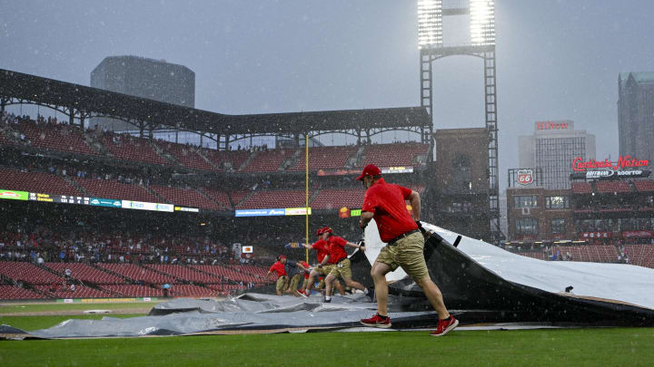 May 4, 2024; St. Louis, Missouri, USA;  St. Louis Cardinals grounds crew pulls the tarp on the field as heavy rain falls during the tenth inning of a game against the Chicago White Sox at Busch Stadium. Mandatory Credit: Jeff Curry-USA TODAY Sports