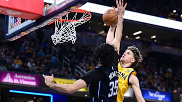 Apr 11, 2025; Indianapolis, Indiana, USA; Indiana Pacers forward Johnny Furphy (12) dunks the ball over Orlando Magic center Goga Bitadze (35) during the second quarter at Gainbridge Fieldhouse. Mandatory Credit: Marc Lebryk-Imagn Images