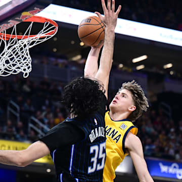Apr 11, 2025; Indianapolis, Indiana, USA; Indiana Pacers forward Johnny Furphy (12) dunks the ball over Orlando Magic center Goga Bitadze (35) during the second quarter at Gainbridge Fieldhouse. Mandatory Credit: Marc Lebryk-Imagn Images