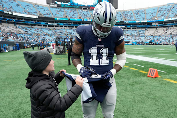 Dallas Cowboys linebacker Micah Parsons signs a jersey for a fan before the game at Bank of America Stadium.