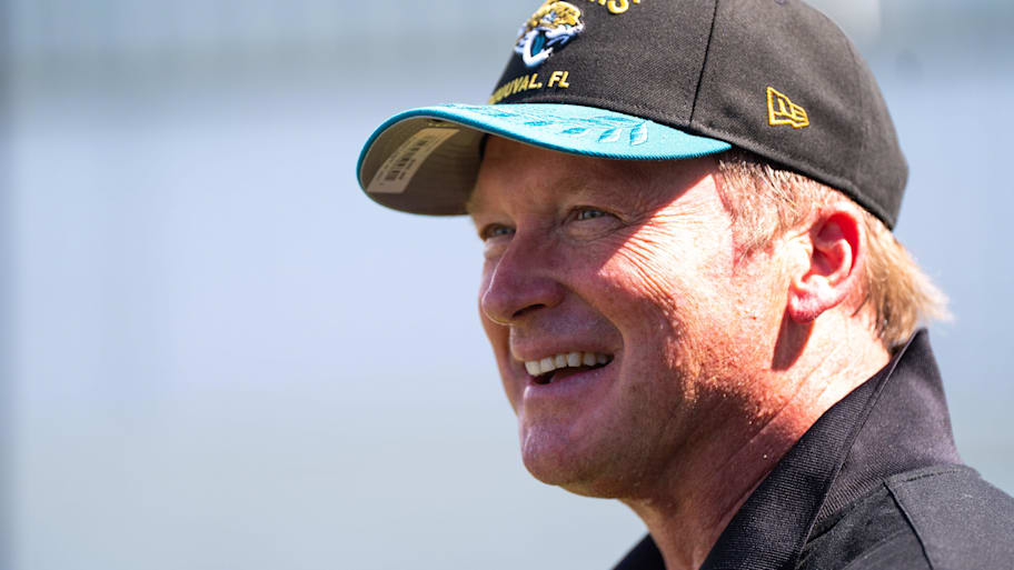 Former NFL coach Jon Gruden laughs while attending an NFL training camp session.