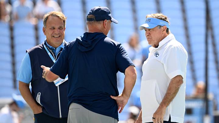 Sep 13, 2025; Chapel Hill, North Carolina, USA; Richmond Spiders head coach Russ Huesman talks to North Carolina Tar Heels general manger Michael Lombardi and head coach Bill Belichick before the game at Kenan Stadium. Mandatory Credit: Bob Donnan-Imagn Images