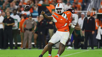 Sep 27, 2024; Miami Gardens, Florida, USA; Miami Hurricanes quarterback Cam Ward (1) throws the football as Virginia Tech Hokies defensive lineman Wilfried Pene (91) attempts a tackle during the second quarter at Hard Rock Stadium. Mandatory Credit: Sam Navarro-Imagn Images