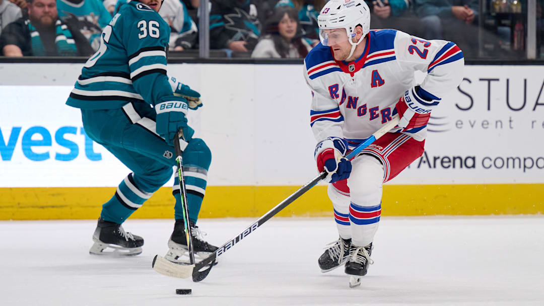 Mar 29, 2025; San Jose, California, USA; New York Rangers defenseman Adam Fox (23) plays the puck against San Jose Sharks defenseman Lucas Carlsson (36) during the first period at SAP Center at San Jose. Mandatory Credit: Robert Edwards-Imagn Images