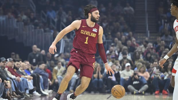 A basketball player dribbling a basketball while wearing a wine and gold uniform.