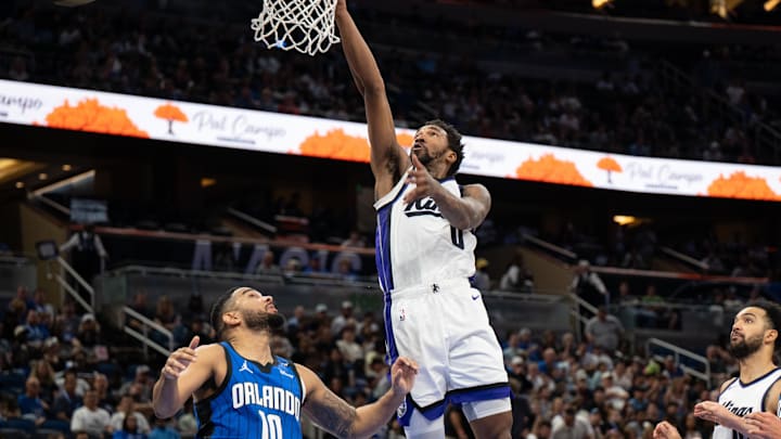 Mar 29, 2025; Orlando, Florida, USA; Sacramento Kings guard Malik Monk (0) lays the ball in over Orlando Magic guard Cory Joseph (10) in the second quarter at Kia Center. Mandatory Credit: Jeremy Reper-Imagn Images