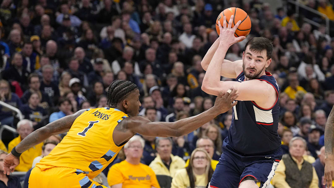 Feb 1, 2025; Milwaukee, Wisconsin, USA;  Connecticut Huskies forward Alex Karaban (11) drives for the basket around Marquette Golden Eagles guard Kam Jones (1) during the first half at Fiserv Forum. Mandatory Credit: Jeff Hanisch-Imagn Images