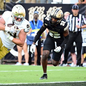 Sep 14, 2024; West Lafayette, Indiana, USA;  Notre Dame Fighting Irish tight end Kevin Bauman (84) dives into the end zone for a touchdown against Purdue Boilermakers defensive back Joseph Jefferson II (32) during the second half at Ross-Ade Stadium. Mandatory Credit: Marc Lebryk-Imagn Images