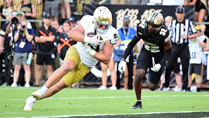 Sep 14, 2024; West Lafayette, Indiana, USA;  Notre Dame Fighting Irish tight end Kevin Bauman (84) dives into the end zone for a touchdown against Purdue Boilermakers defensive back Joseph Jefferson II (32) during the second half at Ross-Ade Stadium. Mandatory Credit: Marc Lebryk-Imagn Images