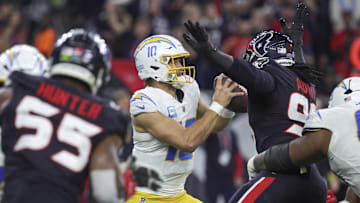 Los Angeles Chargers quarterback Justin Herbert moves with the ball as Houston Texans defensive end Denico Autry defends.