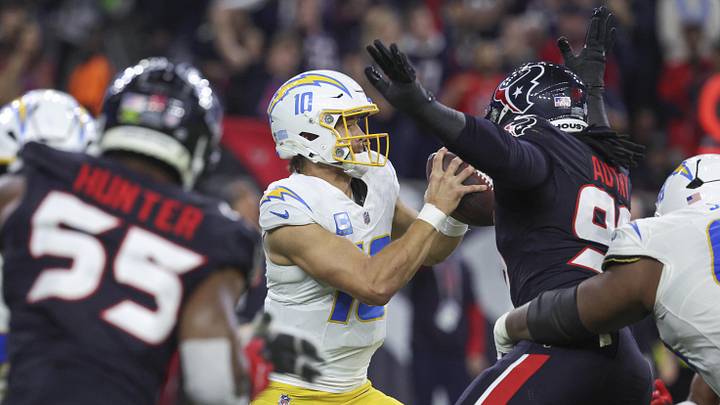 Los Angeles Chargers quarterback Justin Herbert moves with the ball as Houston Texans defensive end Denico Autry defends.
