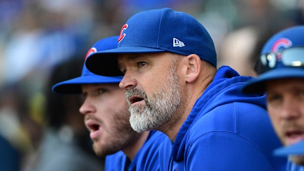 Former Chicago Cubs manager David Ross looks on while wearing a blue hat and hoodie.