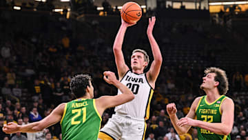 Feb 19, 2025; Iowa City, Iowa, USA; Iowa Hawkeyes forward Payton Sandfort (20) goes to the basket as Oregon Ducks forward Brandon Angel (21) and center Nate Bittle (32) defend during the second half at Carver-Hawkeye Arena. Mandatory Credit: Jeffrey Becker-Imagn Images