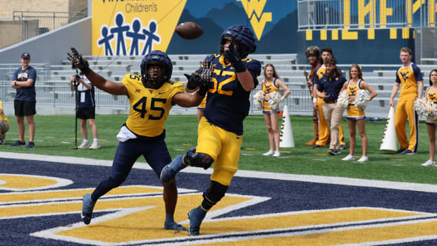 West Virginia University redshirt freshman offensive lineman attempts to haul in a pass against senior defensive end Taurus Simmons during a 1v1 drill in the 2024 Gold-Blue Spring Game.