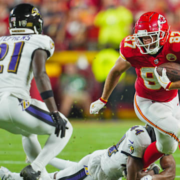 Kansas City Chiefs tight end Travis Kelce (87) is tackled by Baltimore Ravens cornerback Marlon Humphrey (44) and cornerback Brandon Stephens (21) during the first half at GEHA Field at Arrowhead Stadium.