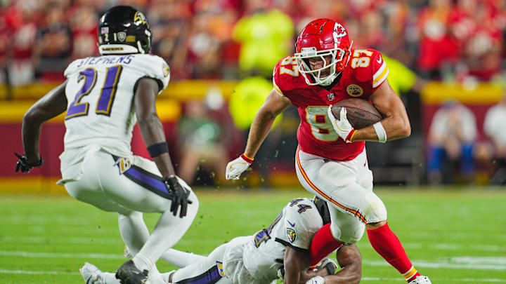 Kansas City Chiefs tight end Travis Kelce (87) is tackled by Baltimore Ravens cornerback Marlon Humphrey (44) and cornerback Brandon Stephens (21) during the first half at GEHA Field at Arrowhead Stadium.