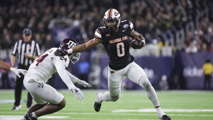 Dec 27, 2023; Houston, TX, USA; Oklahoma State Cowboys running back Ollie Gordon II (0) runs with the ball as Texas A&M Aggies linebacker Chris Russell Jr. (24) attempts to make a tackle during the first quarter at NRG Stadium. Mandatory Credit: Troy Taormina-USA TODAY Sports