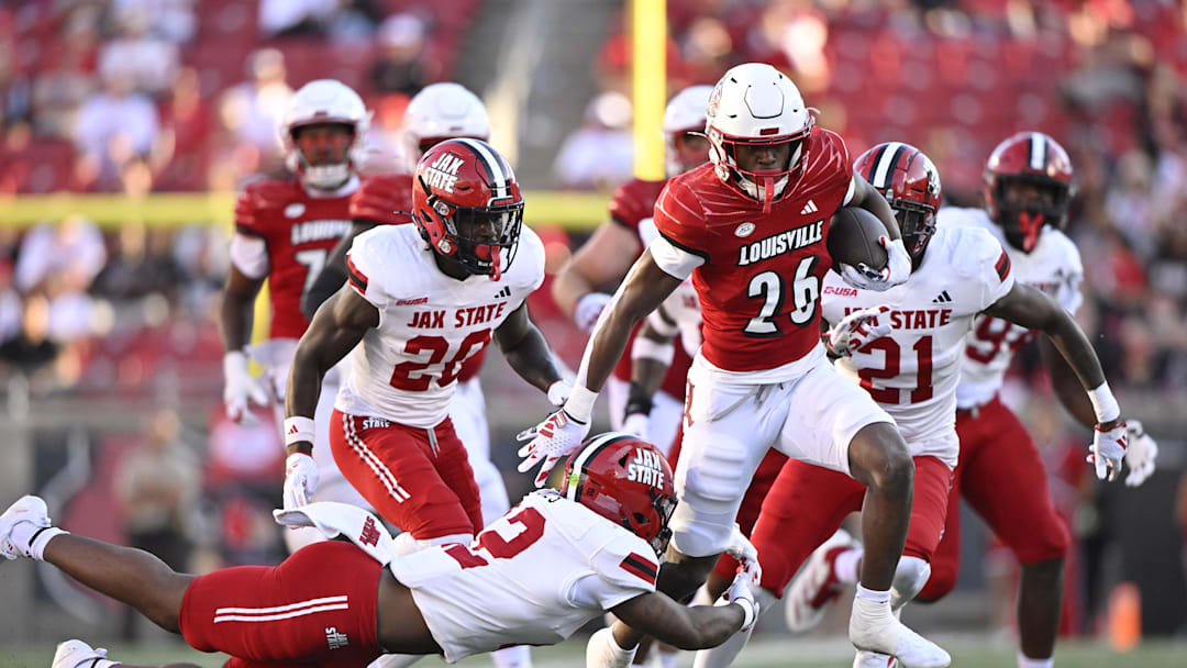 Sep 7, 2024; Louisville, Kentucky, USA;  Louisville Cardinals running back Duke Watson (26) escapes the tackle of Jacksonville State Gamecocks safety Malcolm Jones (12) during the second half at L&N Federal Credit Union Stadium. Louisville defeated Jacksonville State 49-14. Mandatory Credit: Jamie Rhodes-Imagn Images