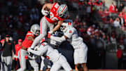 Nov 22, 2025; Columbus, Ohio, USA; Ohio State Buckeyes tight end Max Klare (86) leaps over Rutgers Scarlet Knights defensive back Kaj Sanders (5) and linebacker Dariel Djabome (8) while running after a catch during the third quarter at Ohio Stadium. Mandatory Credit: Joseph Maiorana-Imagn Images