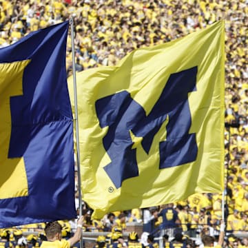 Oct 4, 2025; Ann Arbor, Michigan, USA;  Michigan Wolverines cheerleader run flags down the field before the game against the Wisconsin Badgers at Michigan Stadium. Mandatory Credit: Rick Osentoski-Imagn Images
