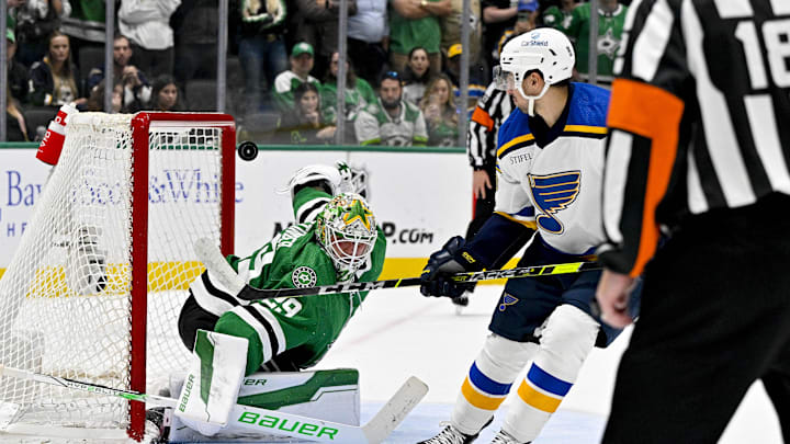 Apr 17, 2024; Dallas, Texas, USA; St. Louis Blues center Jordan Kyrou (25) looks on as his shot hits the crossbar behind Dallas Stars goaltender Jake Oettinger (29) during the overtime shootout at the American Airlines Center. Mandatory Credit: Jerome Miron-Imagn Images