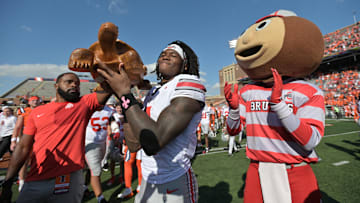 Oct 11, 2025; Champaign, Illinois, USA; Ohio State Buckeyes wide receiver Jeremiah Smith (4) celebrates winning the Illinibuck Trophy with Ohio State Buckeyes mascot Brutus following a win over the Illinois Fighting Illini at Memorial Stadium. Mandatory Credit: Ron Johnson-Imagn Images