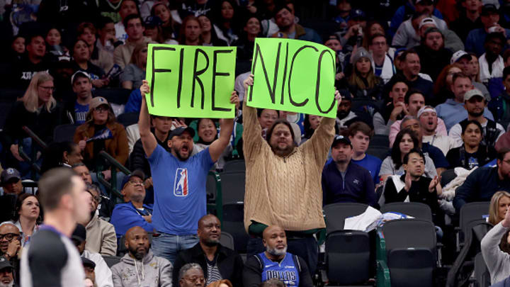 Two Dallas Mavericks fans hold up signs during the team’s game against the Sacramento Kings. They would be escorted out of the building.