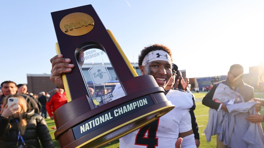 Trinidad Chambliss holds the Division II national championship trophy aloft in 2024.