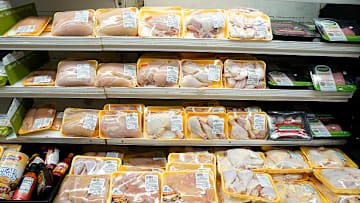 A supermarket poultry case containing packages of raw chicken.