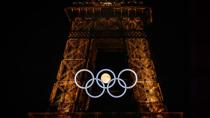 The moon rises behind the Olympic rings displayed on the Eiffel Tower in Paris on July 22, 2024, ahead of the Paris 2024 Olympic Games.