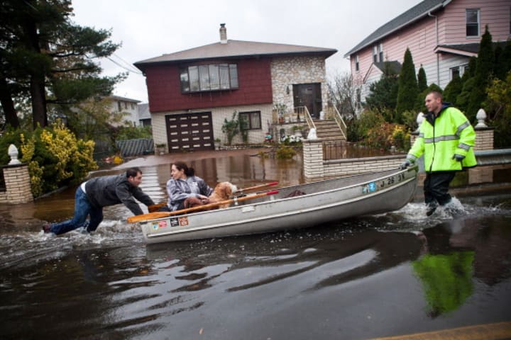 Rescuers carry a woman and her dog in a flooded New Jersey street following Superstorm Sandy in 2012.