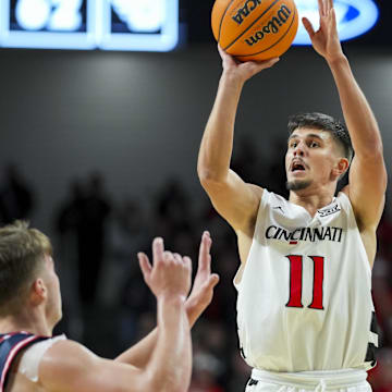 Nov 11, 2025; Cincinnati, Ohio, USA; Cincinnati Bearcats guard Kerr Kriisa (11) shoots against Dayton Flyers guard Jordan Derkack (4) in the second half at Fifth Third Arena. Mandatory Credit: Aaron Doster-Imagn Images