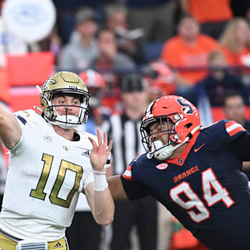 Sep 7, 2024; Syracuse, New York, USA; Georgia Tech Yellow Jackets quarterback Haynes King (10) throws a pass under pressure by defensive lineman Kevin Jobity Jr. (94) in the fourth quarter at the JMA Wireless Dome. Mandatory Credit: Mark Konezny-Imagn Images