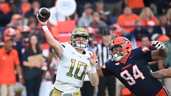 Sep 7, 2024; Syracuse, New York, USA; Georgia Tech Yellow Jackets quarterback Haynes King (10) throws a pass under pressure by defensive lineman Kevin Jobity Jr. (94) in the fourth quarter at the JMA Wireless Dome. Mandatory Credit: Mark Konezny-Imagn Images