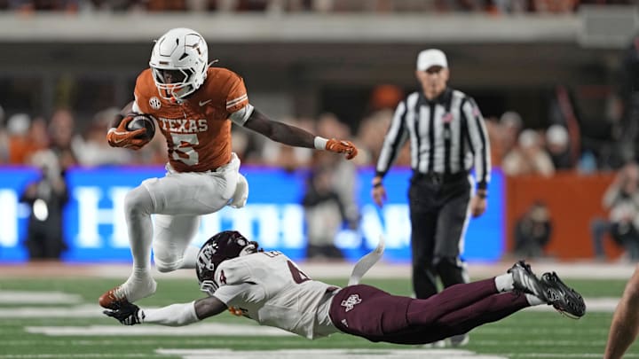 Nov 28, 2025; Austin, Texas, USA; Texas Longhorns running back Quintrevion Wisner (5) leaps over Texas A&M Aggies cornerback Will Lee III (4) during the first half against the Texas Longhorns at Darrell K Royal-Texas Memorial Stadium. Mandatory Credit: Scott Wachter-Imagn Images