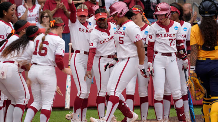 Oklahoma infielder Ella Parker (5) is greeted at home by teammates after hitting home run in the fourth inning of a softball game in the Norman Regional of the NCAA Tournament between the University of Oklahoma Sooners (OU) and the California Golden Bears at Love's Field in Norman, Okla., Sunday, May 18, 2025. Oklahoma won 12-1.