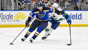 Mar 20, 2025; St. Louis, Missouri, USA;  St. Louis Blues defenseman Justin Faulk (72) controls the puck as Vancouver Canucks right wing Brock Boeser (6) defends during the first period at Enterprise Center. Mandatory Credit: Jeff Curry-Imagn Images